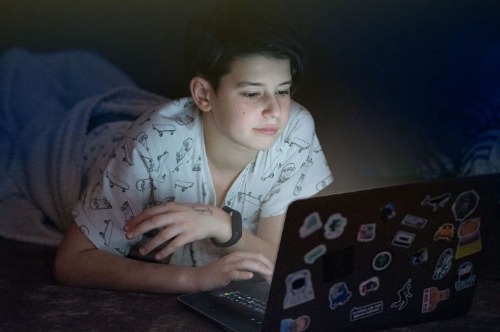 Pois pidžaamades kasutab voodis sülearvutit.