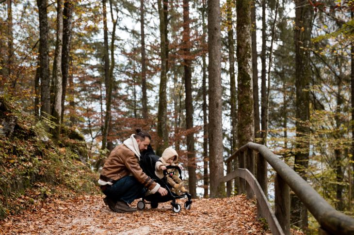 Isa kontrollib matkarajal kas lapsel on jalutuskärus kõik hästi.